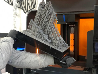 A person removes a complex 3D-printed object from a Formlabs Fuse SLS printer.