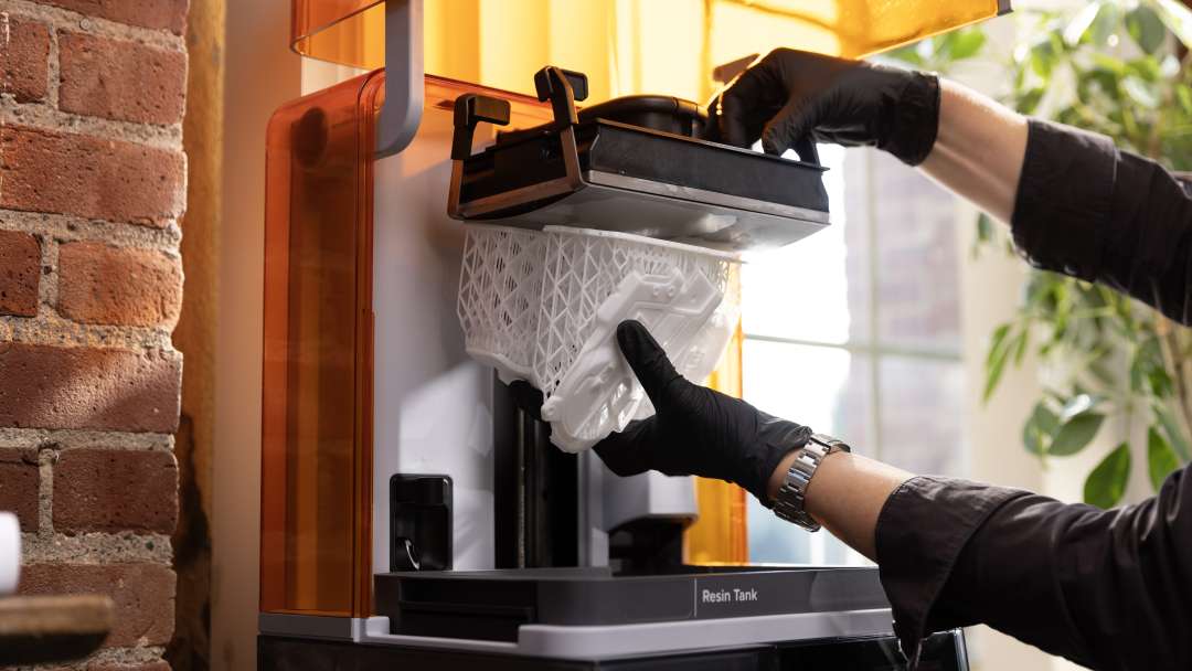 Процесс извлечения печатной платформы из фотополимерного 3D-принтера Formlabs после завершения SLA-печати.
