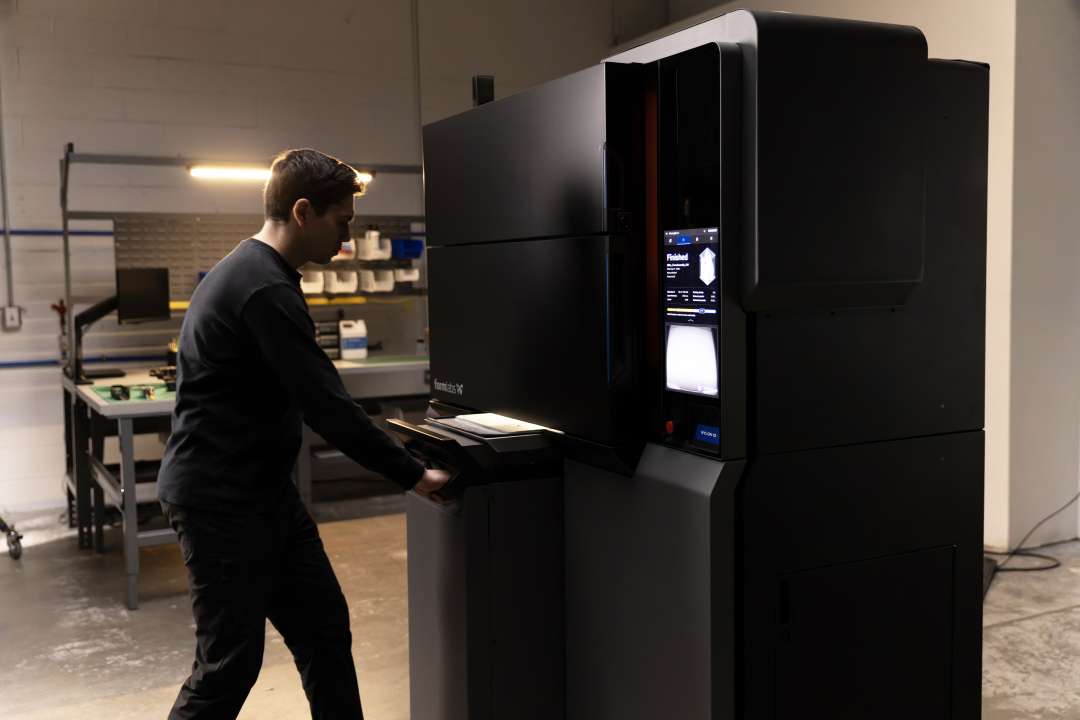Оператор встановлює Formlabs Fuse X1 Build Unit у відсік SLS-принтера Fuse X1; сенсорний екран підтверджує завершення попереднього завдання