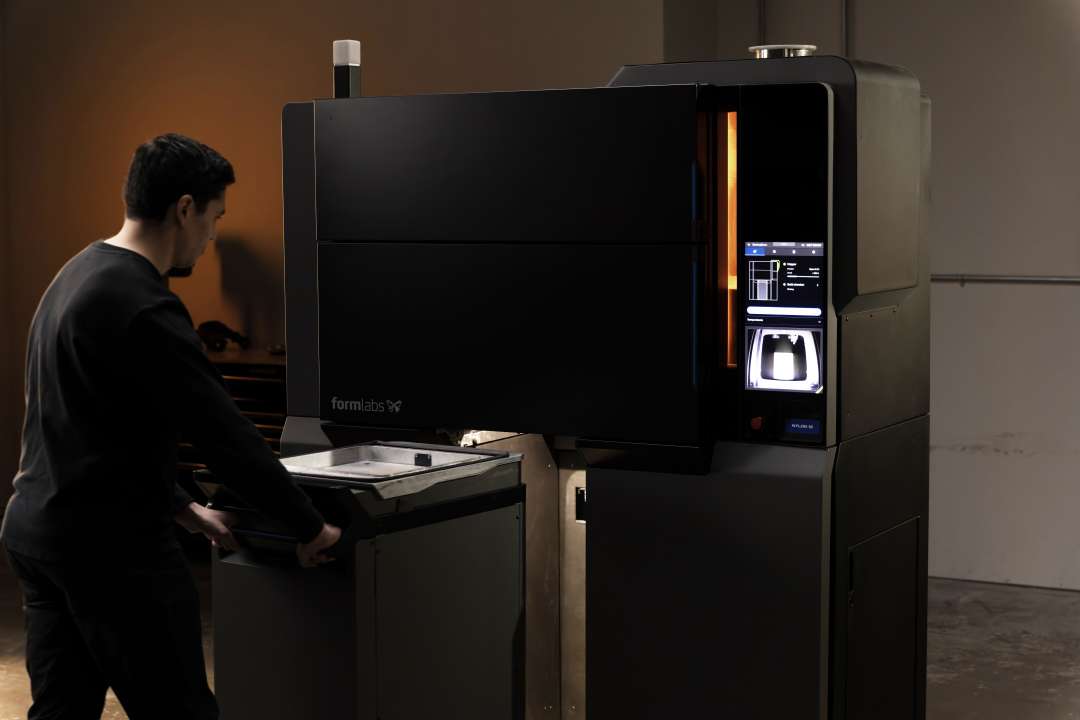 Оператор завантажує порошок у відкритий бункер у верхній частині Formlabs Fuse X1 перед виробничим запуском