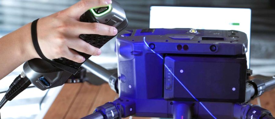 The SimScan 42 Gen2 scanner precisely capturing data from a black and reflective car part, demonstrating its advanced surface handling capabilities.