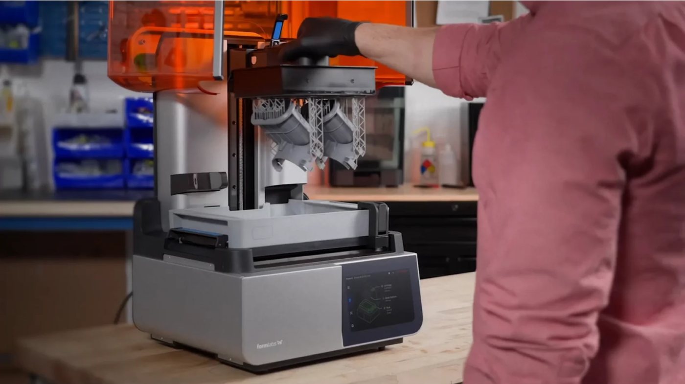 Оператор снимает готовые SLA-модели с платформы Build Platform принтера Formlabs Form 4 после завершения 3D-печати