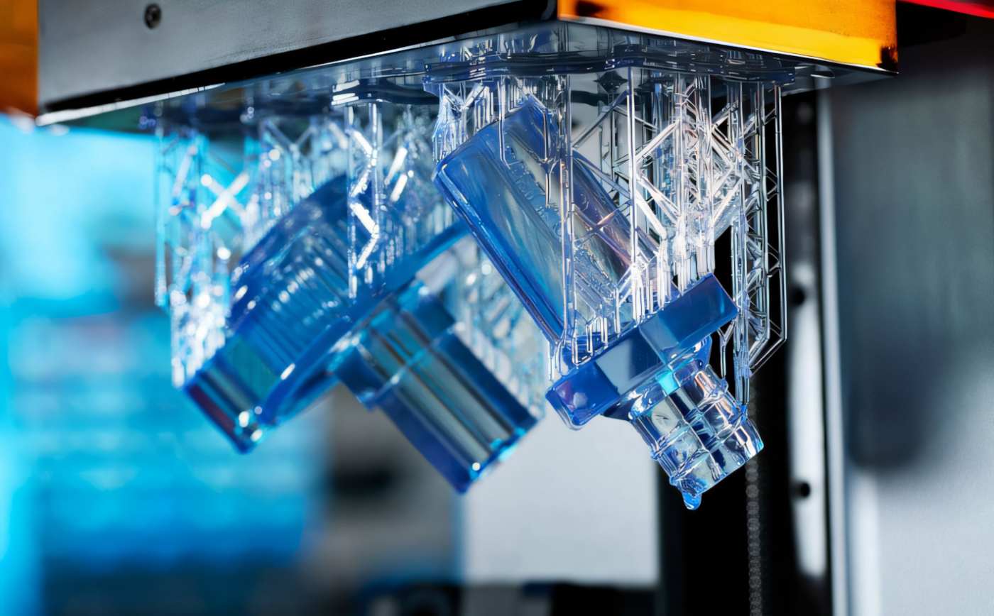 Прозрачные фотополимерные детали, напечатанные на 3D-принтере Formlabs Form 4, непосредственно после завершения печати на платформе с поддержками, готовые к мойке и постобработке.